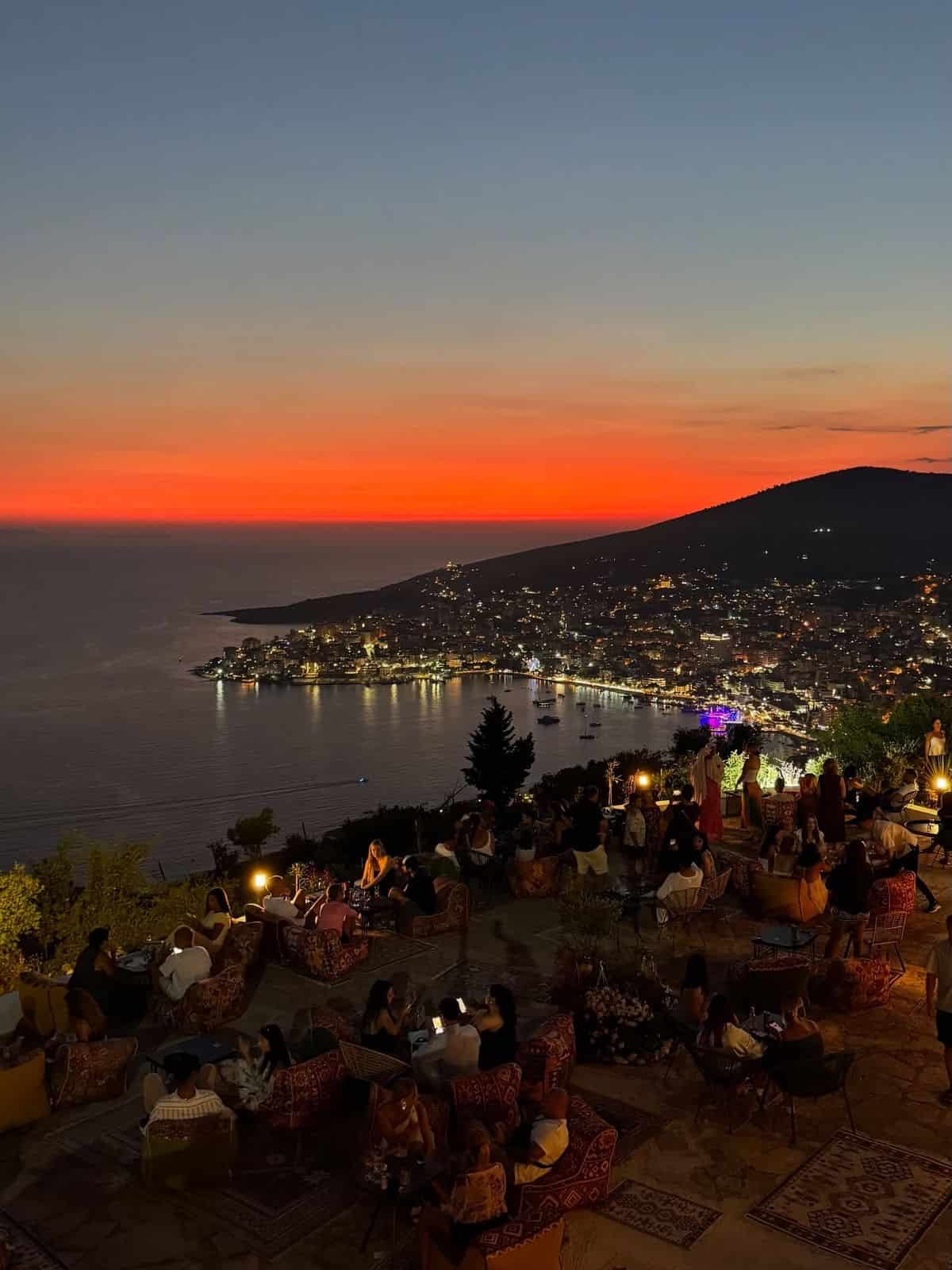 Stunning sunset overlooking a lively seaside terrace with people enjoying evening views, perfect for travel and leisure SEO.