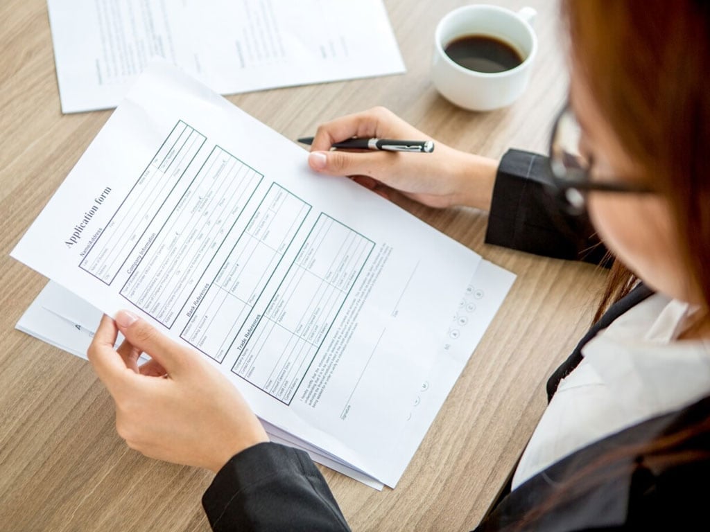 Person reviewing Albanian work permit with a pen and coffee.
