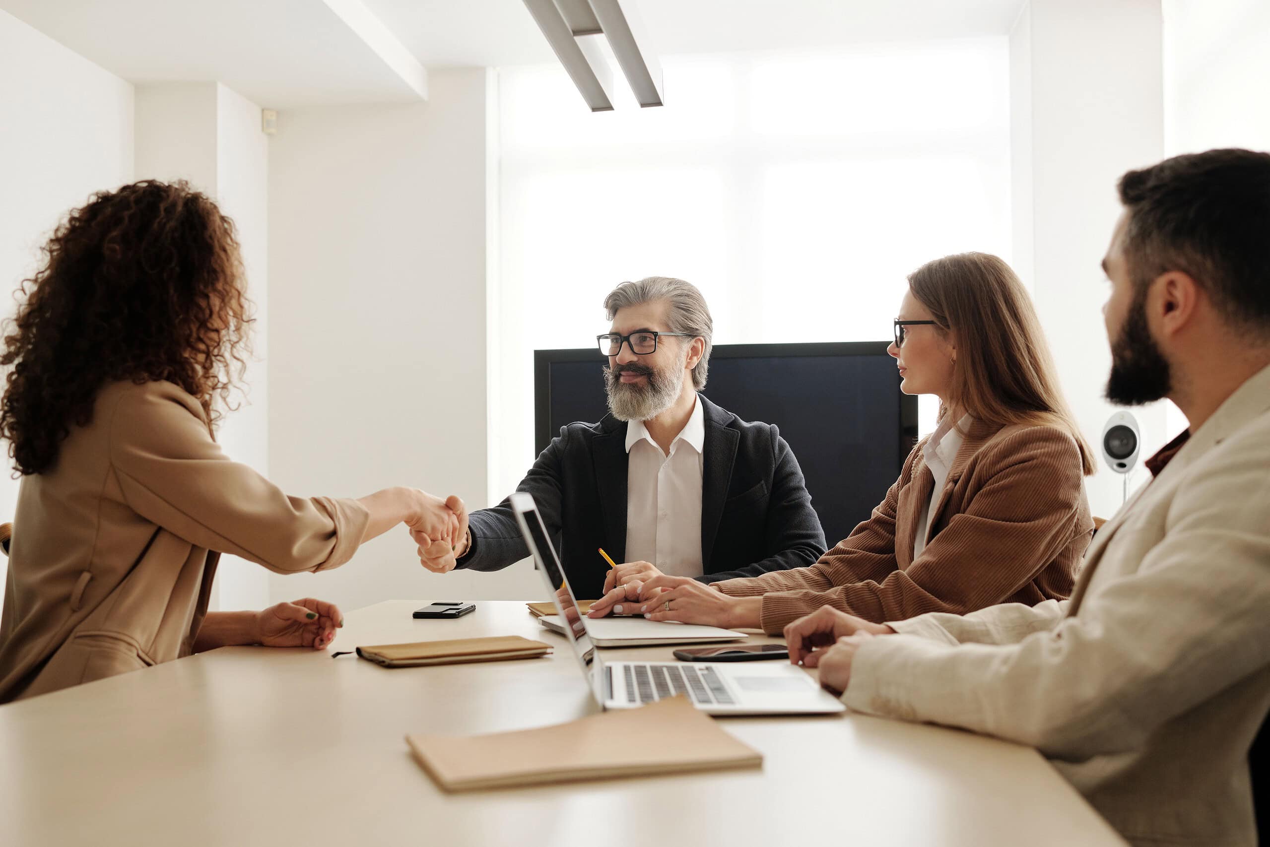 Business professionals shaking hands in a modern office setting.